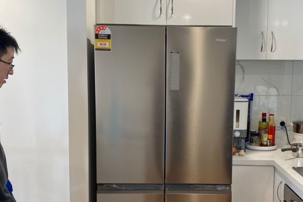Technician inspecting a double-door fridge during a repair service in Melbourne