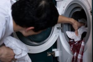 man getting the clothes out from dryer, a malfunctioning heat pump or resistance automatically means partial drying