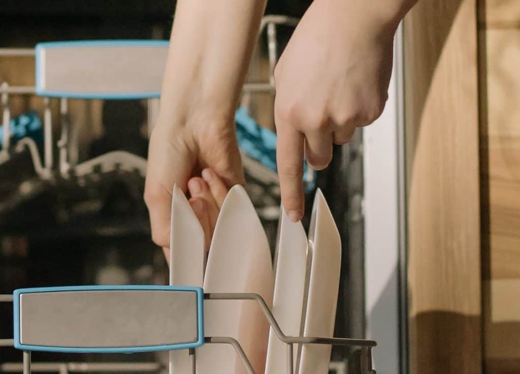 Remove Dishes A hand removing plates in a dishwasher