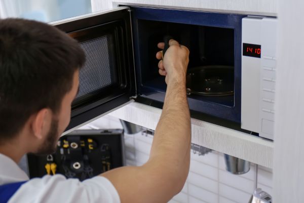 a quality appliance repair technician repairing a microwave oven